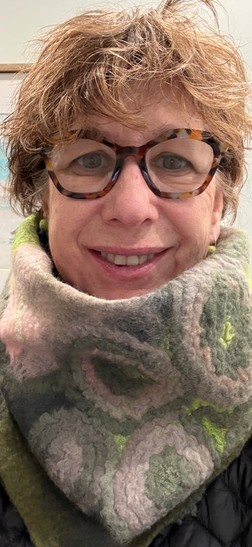 Person wearing a patterned scarf and glasses with a blurred background